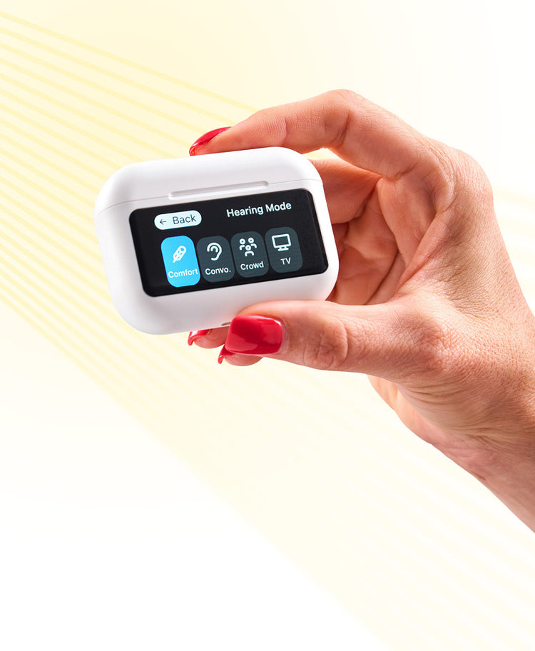 A hand with red nails holds a white device displaying a screen with four hearing mode options: Comfort, Convo, Crowd, and TV.